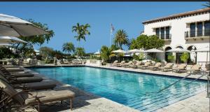 a swimming pool with chairs and umbrellas next to a building at SoCal Lux on Miramar in Los Angeles