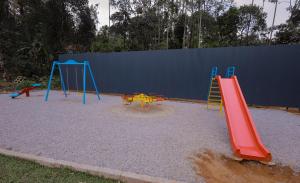 ein Spielplatz mit drei Schaukeln und einer Rutsche in der Unterkunft Century Village Resort in Mananthavady