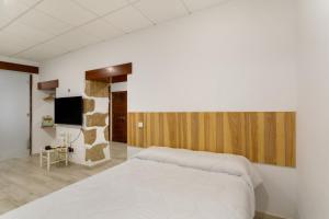 a bedroom with a white bed and a tv at Eva García Naranjo in Las Palmas de Gran Canaria
