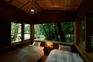 zwei Betten in einem Zimmer mit großem Fenster in der Unterkunft ist - Aokinodaira Field in Kawakami