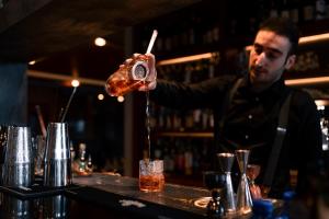 a bartender making a drink at a bar at SOLEA DOLOMITI Boutique Hotel in Fai della Paganella