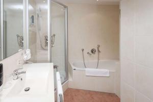a bathroom with a tub and a sink and a shower at Hotel Mondial Munich in Munich +43 photos