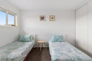 a room with two beds and a table in it at Contemporary & Central in Exclusive Sandy Bay in Sandy Bay