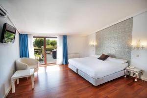 a bedroom with a white bed and a sliding glass door at Hotel Conde Rodrigo II by eme hoteles in Ciudad-Rodrigo