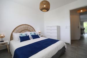 Un dormitorio con una cama grande con almohadas azules. en Le Flamboyant de Delna, en Saint-François