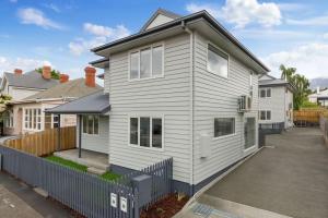 ein weißes Haus mit einem Zaun davor in der Unterkunft Contemporary with Courtyard by Sandy Bay Delights in Sandy Bay