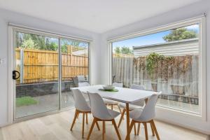 ein weißes Esszimmer mit einem weißen Tisch und Stühlen in der Unterkunft Contemporary with Courtyard by Sandy Bay Delights in Sandy Bay