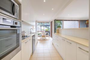 a kitchen with white cabinets and a large window at The Moorings 23 4 Cromarty Rd air con pool and waterfront in Soldiers Point