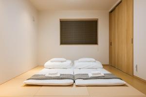 three beds in a room with a window at Irodori Hotel KOU in Fukuoka