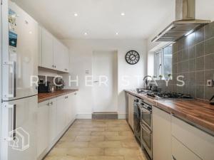 a kitchen with white cabinets and a clock on the wall at Watford Large 5BR Home - Contractors & Families in Watford