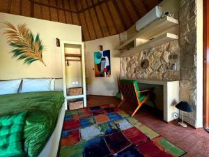 a bedroom with a bed and a stone wall at Jungle Circle Uluwatu in Uluwatu