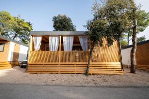 una casa con una valla de madera con cortinas blancas en Mobile Home Lotus, en Biograd na Moru