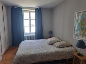 ein Schlafzimmer mit einem Bett mit blauen Vorhängen und einem Fenster in der Unterkunft Clos St Vaast près plage et port in Saint-Vaast-la-Hougue