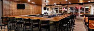 a bar with a long wooden counter and black chairs at Graduate by Hilton Tempe in Tempe