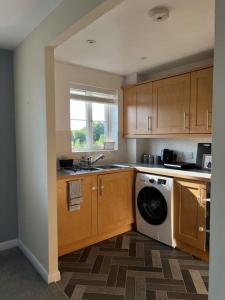 eine Küche mit Waschmaschine und Fenster in der Unterkunft Cosy 2 Bed Service Apartment Netflix Hideaway Family Couples Staycation Tredegar Park Celtic Manor ICC Wales in Lower Clapton + 15 Fotos