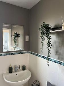 ein Badezimmer mit Waschbecken und Spiegel in der Unterkunft Cosy 2 Bed Service Apartment Netflix Hideaway Family Couples Staycation Tredegar Park Celtic Manor ICC Wales in Lower Clapton