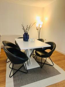 a white table with black chairs and a vase on it at StayWorkHerzo in Herzogenaurach +3 photos