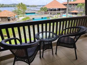 a balcony with two chairs and a view of a pool at Sebana Cove Resort in Pengerang