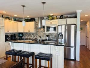 a kitchen with white cabinets and a stainless steel refrigerator at Blue Sunset in Holden Beach