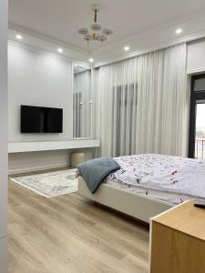 a bedroom with a bed and a flat screen tv at Scandinavian Style Apartment in Fergana