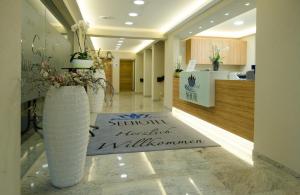 un vestíbulo con 2 vasijas blancas grandes y una alfombra de bienvenida en Seehotel Forst, en Forst