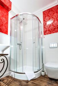 a glass shower in a bathroom with red walls at Hotel POD HERBEM -POKOJE OZONOWANE in Białystok