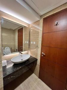 a bathroom with a sink and a wooden door at Panbil Residence Apartment Batam in Kangboi