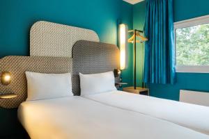 a bedroom with a large white bed with a blue wall at B&B HOTEL Liège Rocourt in Liège