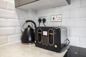 a black toaster and a tea kettle on a counter at Bountrees Apartment in Jedburgh