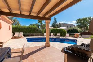een patio met een zwembad en een houten pergola bij Beach Villa Margot by Sealand Villas in Port de Pollença