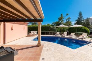 een zwembad met stoelen en parasols op een patio bij Beach Villa Margot by Sealand Villas in Port de Pollença +22 foto's