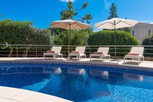 een groep stoelen en parasols naast een zwembad bij Beach Villa Margot by Sealand Villas in Port de Pollença