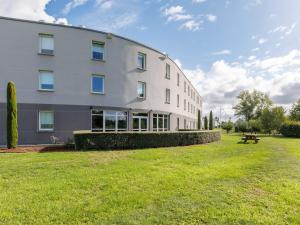 a large building with a grassy yard in front of it at B&B HOTEL Clermont-Ferrand Nord Riom in Riom