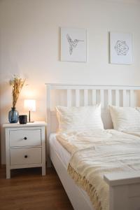 a bedroom with a white bed with a night stand and a lamp at Hniezdo v Raji 2 - Luxury rest apartment in the hearth of Spišská Nová Ves in Spišská Nová Ves