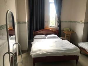 a small bedroom with a bed and a window at Khách sạn Quốc Việt in Bao Loc +5 photos
