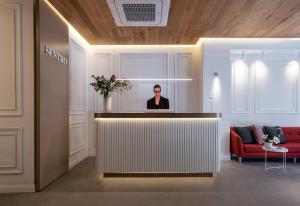 Eine Frau sitzt an einem Empfangstresen in einer Lobby in der Unterkunft Sentro Boutique Hotel in Sofia