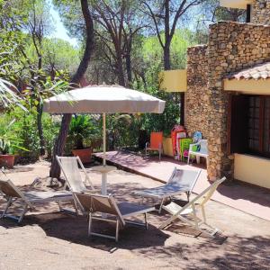 grupa krzeseł i parasol na patio w obiekcie Villa Giancarla Santa Margherita di Pula w mieście Santa Margherita di Pula