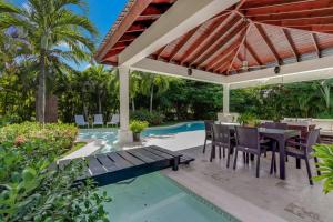 a patio with a table and chairs next to a swimming pool at Beautiful Villa with Pool, Gym & Maid in Punta Cana