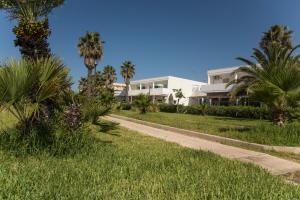 a walkway in front of a house with palm trees at Residence Baia D'Oro in Torre Mozza