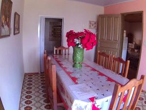 una mesa con un jarrón con flores rojas. en Casa para temporada da Vó Cida, en Olímpia