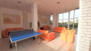 a room with a ping pong table and orange chairs at Студия Мир Авангарда in Sunny Beach