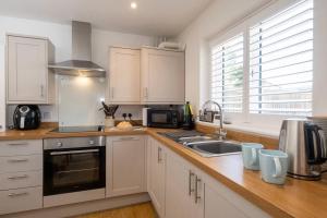 a kitchen with white cabinets and a sink at 1 Buxlow Cottages in Aldringham