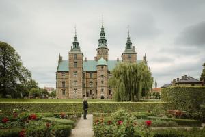una persona caminando por un jardín frente a un castillo en 2BR with Amazing City Skyline View, en Copenhague