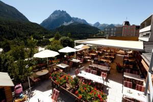 um restaurante ao ar livre com mesas, cadeiras e montanhas em Hotel Astras em Scuol