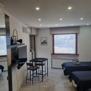 a living room with a table and a bed and a television at Appartamento Sanzio, centro Monfalcone in Monfalcone