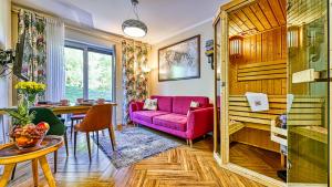 a living room with a purple couch and a table at Apartament Podróżniczy z prywatną Sauną blisko Elementsa - 5D Apartments in Świeradów-Zdrój