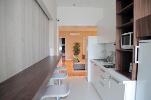 a kitchen with white cabinets and a counter with white chairs at Hostel Karavan Inn in Belgrade