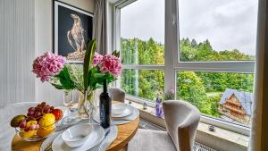 jadalnia ze stołem z kwiatami i oknem w obiekcie Apartament SPA 56 Resort Kozubnik blisko Szczyrk - 5D Apartamenty w mieście Porąbka