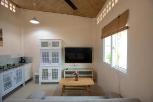 The Hidden Lagoon Resort - Exclusively for Adults في شاطئ راوايْ: غرفة معيشة مع طاولة وتلفزيون