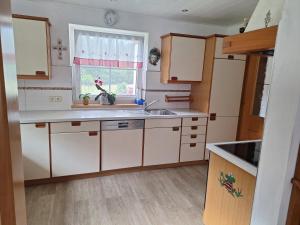 a kitchen with white cabinets and a sink and a window at Ferienhaus Melchartboden in Paal